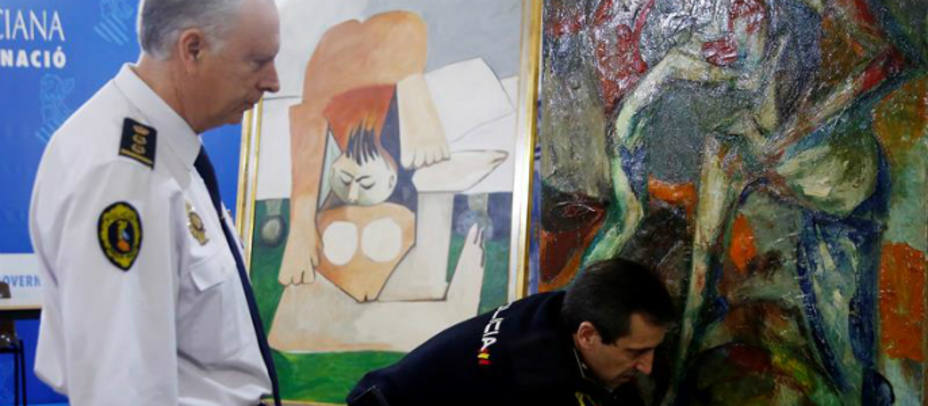 Un policía nacional y un policía autonómico estudian una de las obras falsas de Picasso, por cuya venta ilícita han sido detenidas ocho personas. EFE/Kai Försterling
