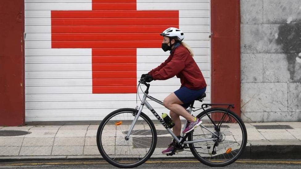 Mujer en bicicleta ante la entrada de ambulancias de la Cruz Roja en Oviedo