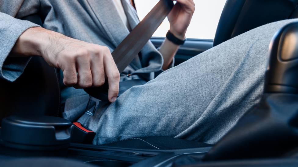 Un conductor se ajusta el cinturón de seguridad en su coche