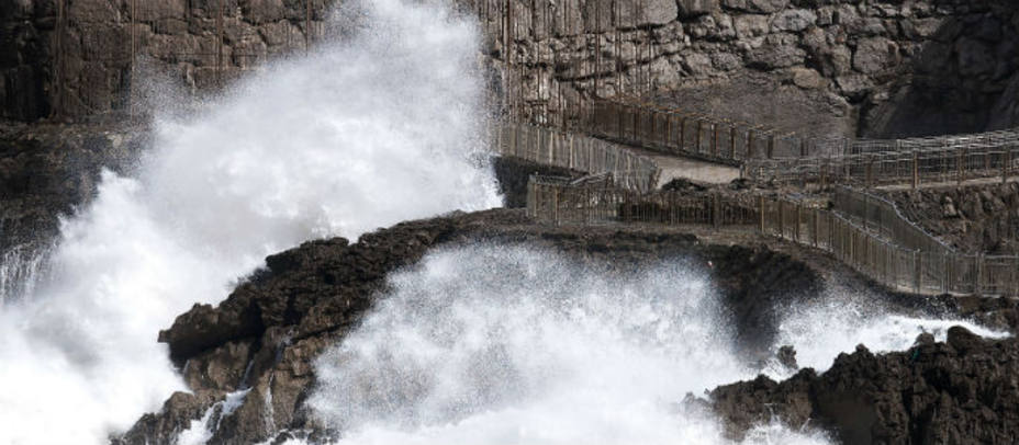 Una persona toma fotografías mientras una ola rompe en el Palacio de la Magdalena en Santander, este miércoles. EFE