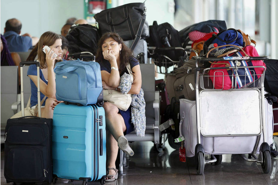 Algunos viajeros esperan la salida de sus vuelos en la Terminal 1 del Aeropuerto de El Prat, en Barcelona. EFE