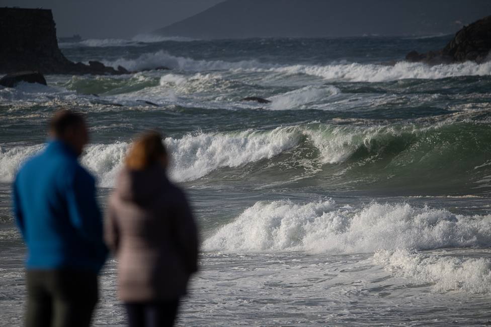 Dos personas observan el mar con olas por el temporal