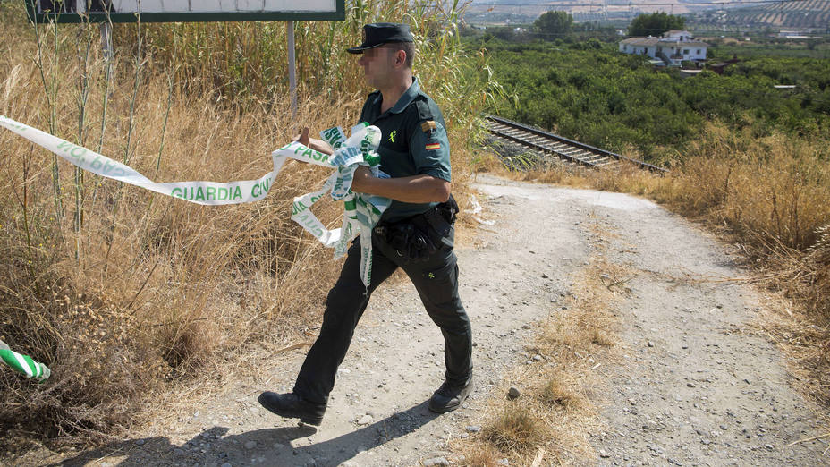 Un Guardia Civil retira la cinta de la zona acotada en la vía férrea donde esta mañana un maquinista de un tren de la línea de Cercanías que une la localidad malagueña de Álora con Málaga