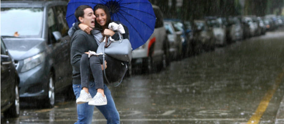 Una pareja cruza una calle de Salou inundada a causa del frente que esta azotando Cataluña y donde se prevee que en algunos puntos puedan superarse los 100 litros por metro cuadrado. EFE