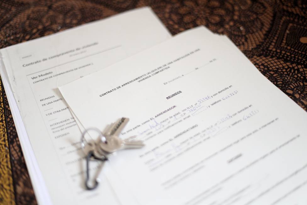 Unas llaves sobre un contrato de compraventa de vivienda y un contrato de arrendamiento (alquiler) de una habitaciÃ³n en una vivienda compartida.