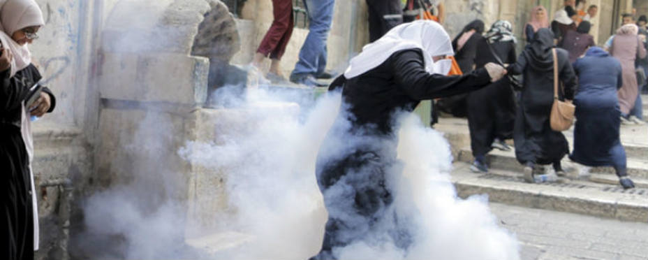 Mujeres palestinas corren ante los botes de humo lanzados por la policía israelí. Reuters