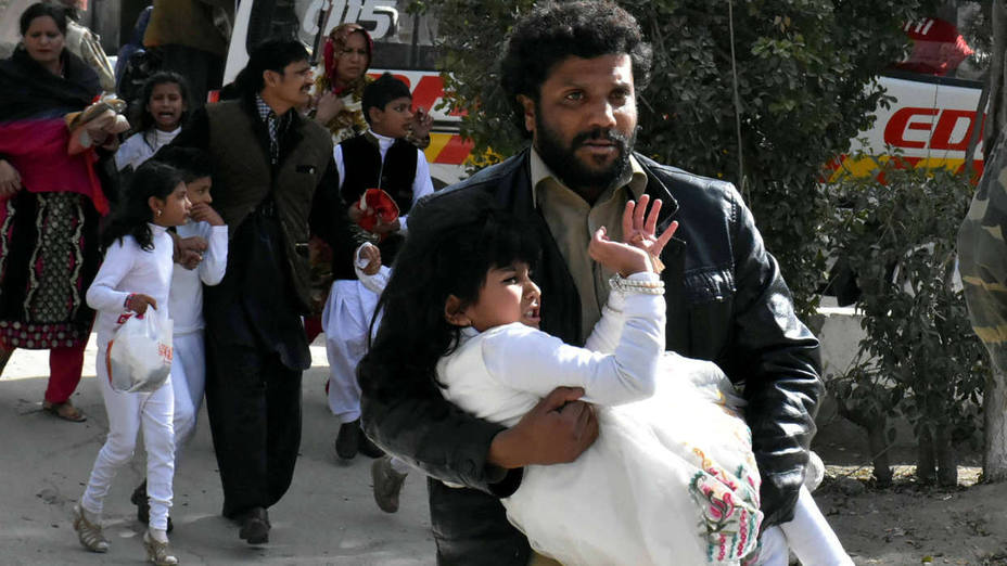 A man carries a girl as he runs out with others after gunmen attacked the Bethel Memorial Methodist Church in Quetta
