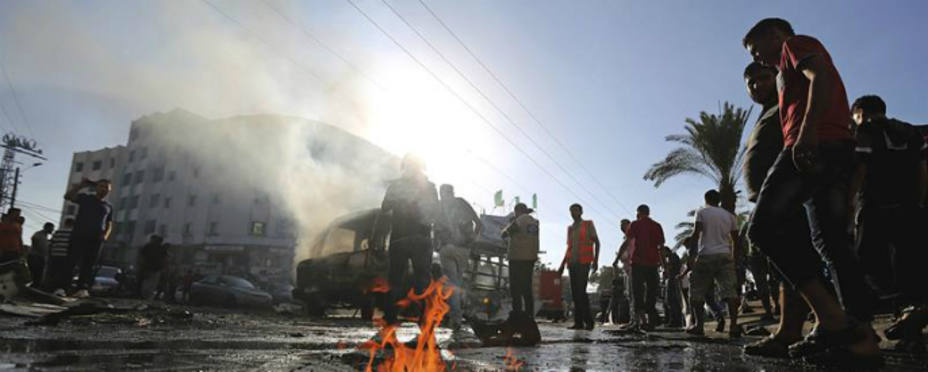 Palestinos inspeccionan autobús alcanzado durante un ataque aéreo (EFE)