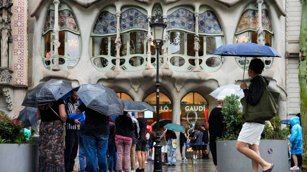 Varios turistas se protegen de la lluvia en las inmediaciones de la Casa Batlló de Barcelona