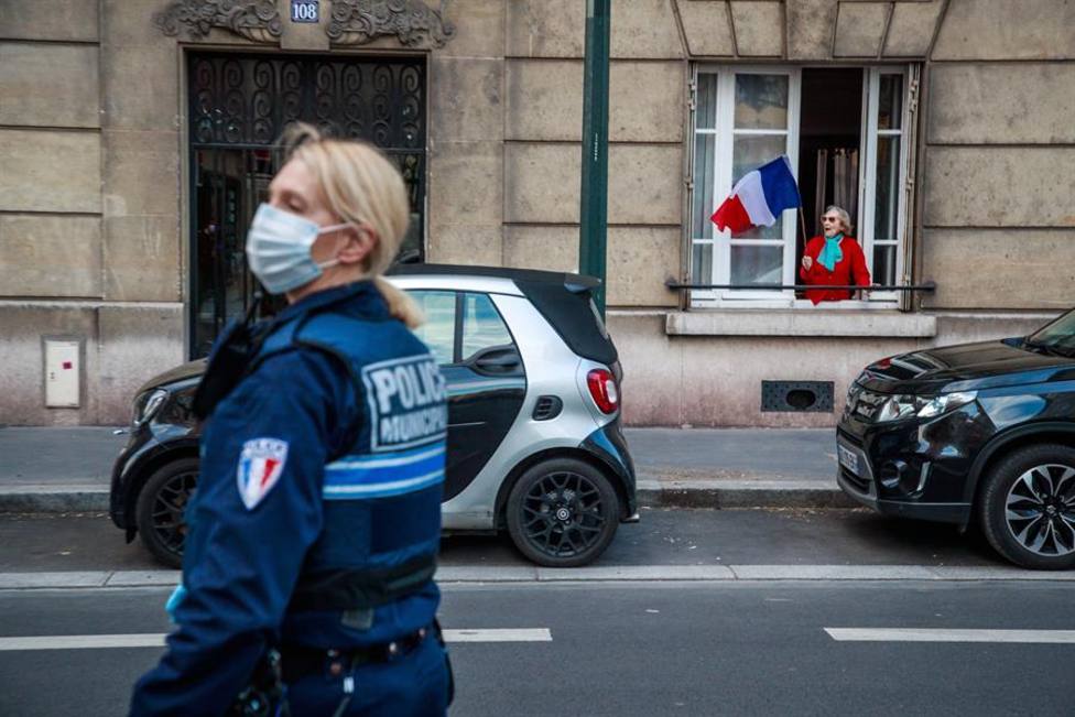 Una ciudadana francesa ondea la bandera de su país delante de una agente de Policía