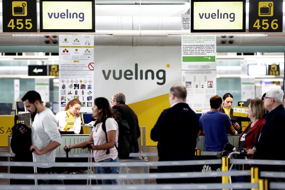 Un grupo de pasajeros ante un mostrador de facturacion de Vueling