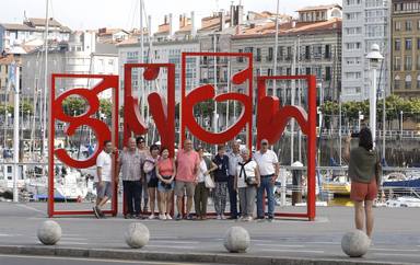 Turistas se fotografían en las letronas de Gijón