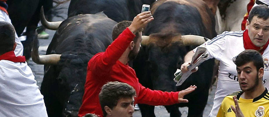 Momento en el que el corredor levanta el móvil para hacerse el selfie ante los toros. EFE