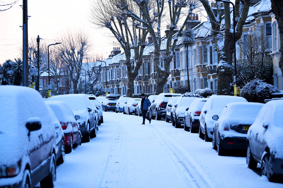 A man walks down a snow covered street in South London