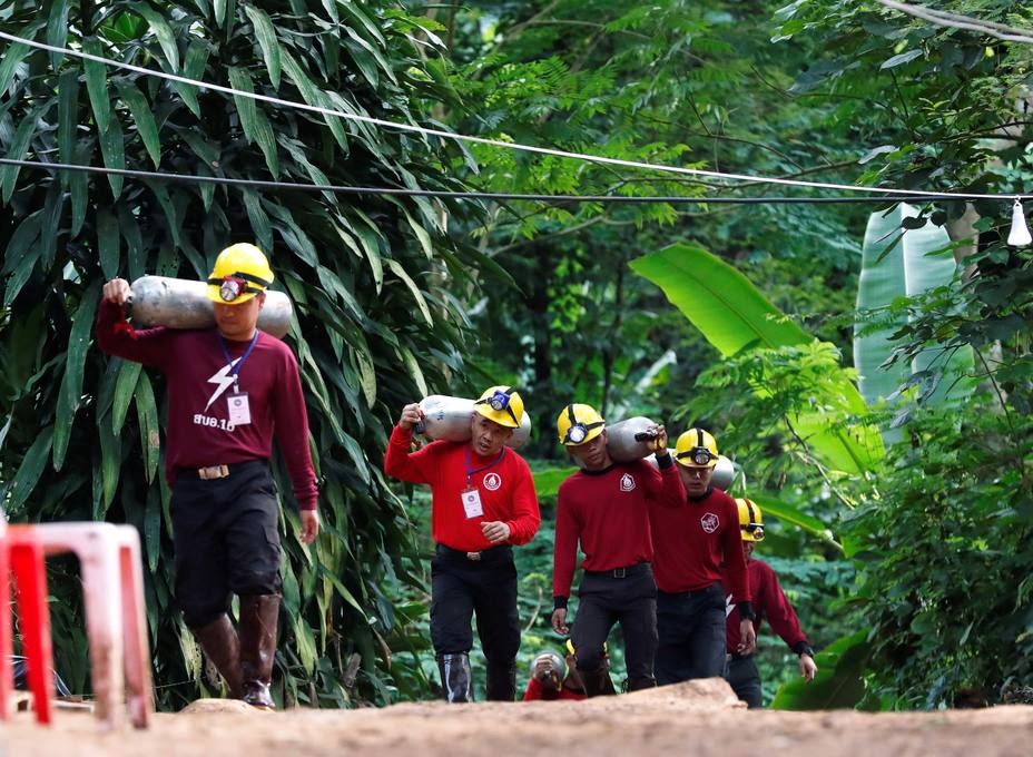 Miembros de los servicios de rescate cargan con botellas de oxígeno mientras continúan las labores de rescate de los doce menores y un adulto atrapados en una cueva en el parque de Khun Nam Nang (Tailandia)