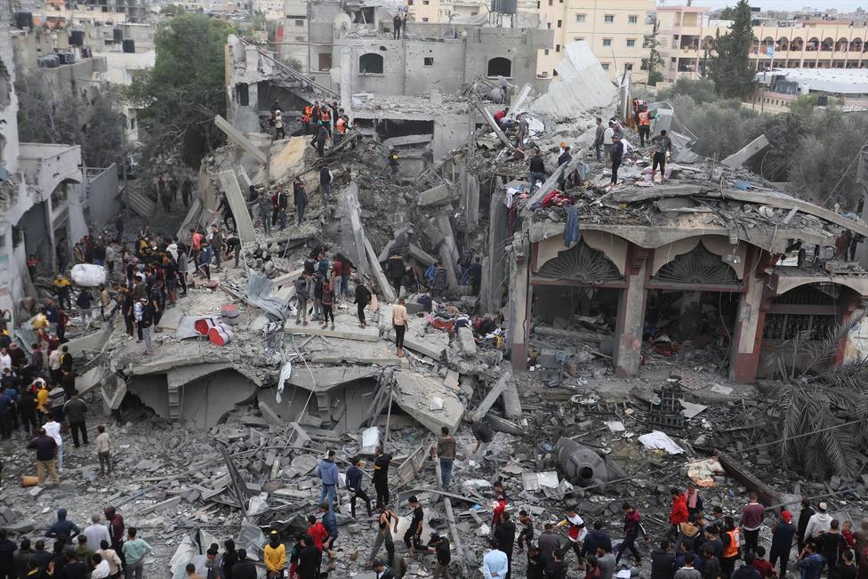 Palestinos entre varios edificios destruidos por los bombardeos de Israel