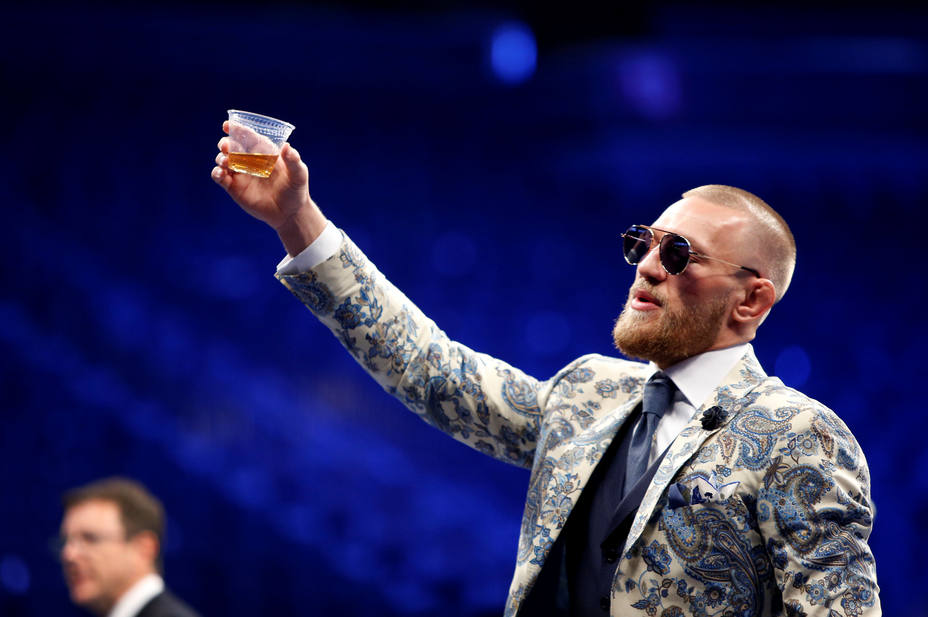 UFC lightweight champion Conor McGregor of Ireland raises a cup of Irish whiskey during post-fight news conference at T-Mobile Arena in Las Vegas