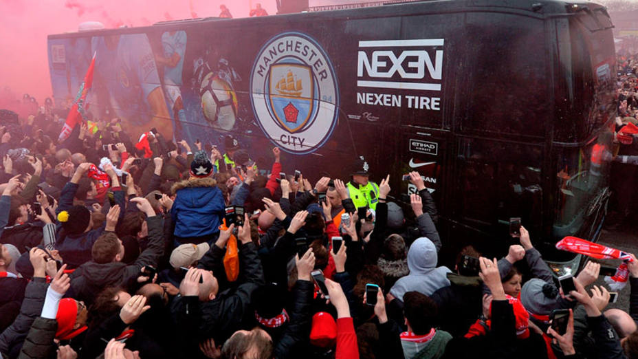 Aficionados del Liverpool reciben con cánticos y bengalas al autobús del Manchester City. EFE