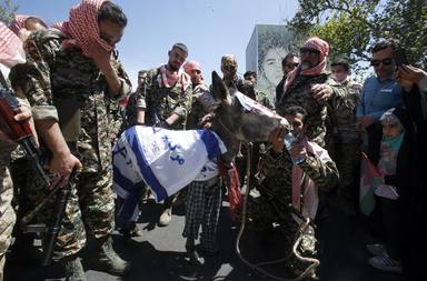Miembros de las fuerzas paramilitares iraníes (Basij) desfilan un burro con la bandera israelí