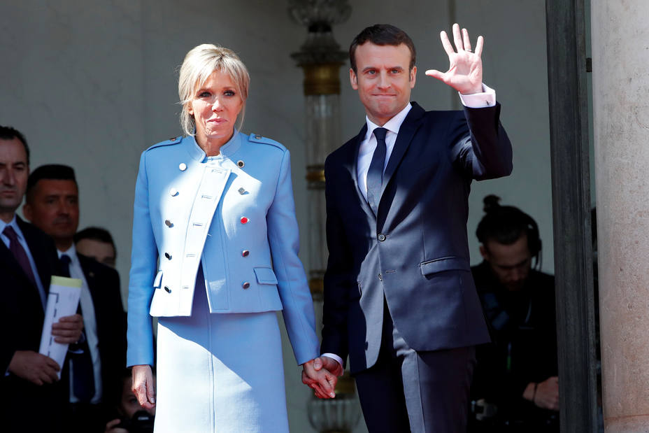 French President Emmanuel Macron and his wife Brigitte Trogneux wave to French President Francois Hollande as he leaves after the handover ceremony at the Elysee Palace in Paris
